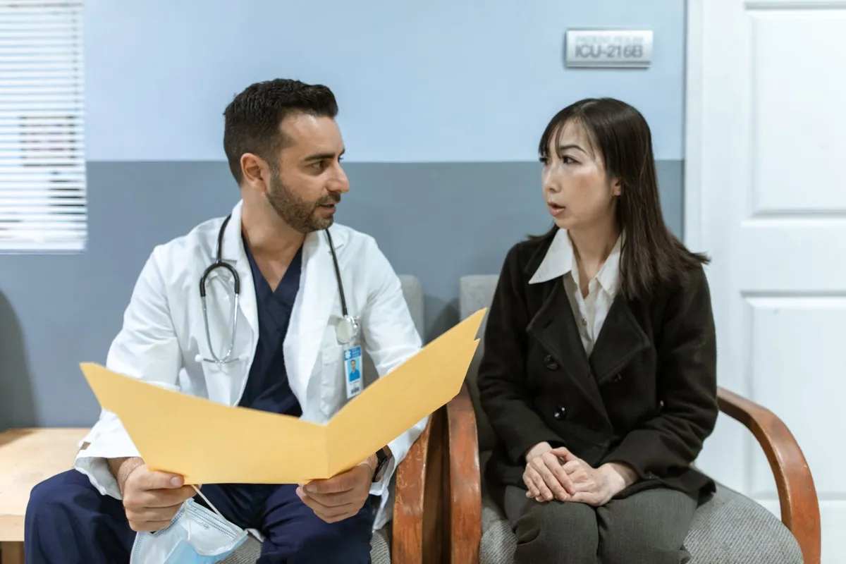 A doctor holding a yellow folder talking with a woman patient